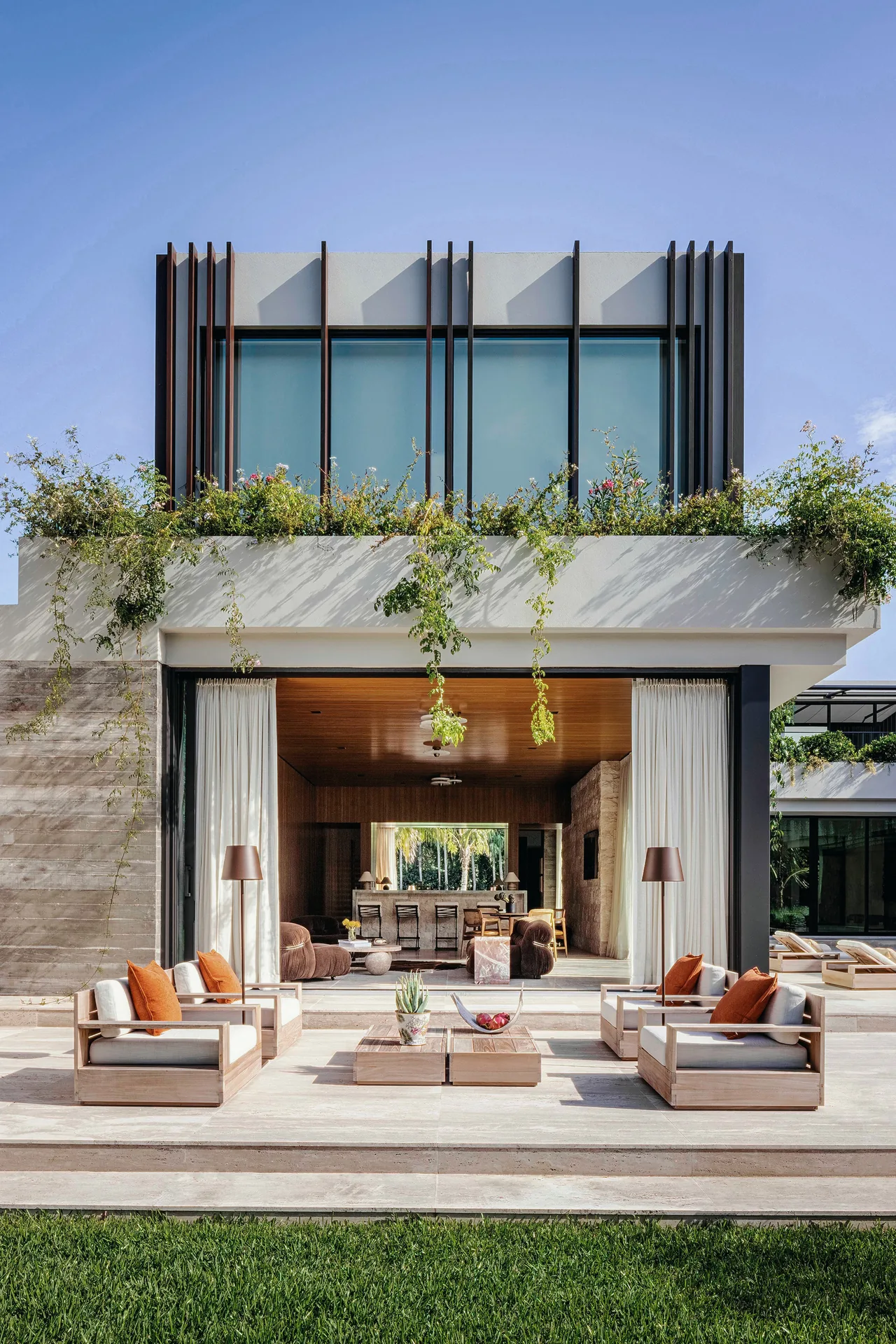 Angel Oaks residence by STRANG Architecture features a modern design with vertical fins and an open patio seating area.