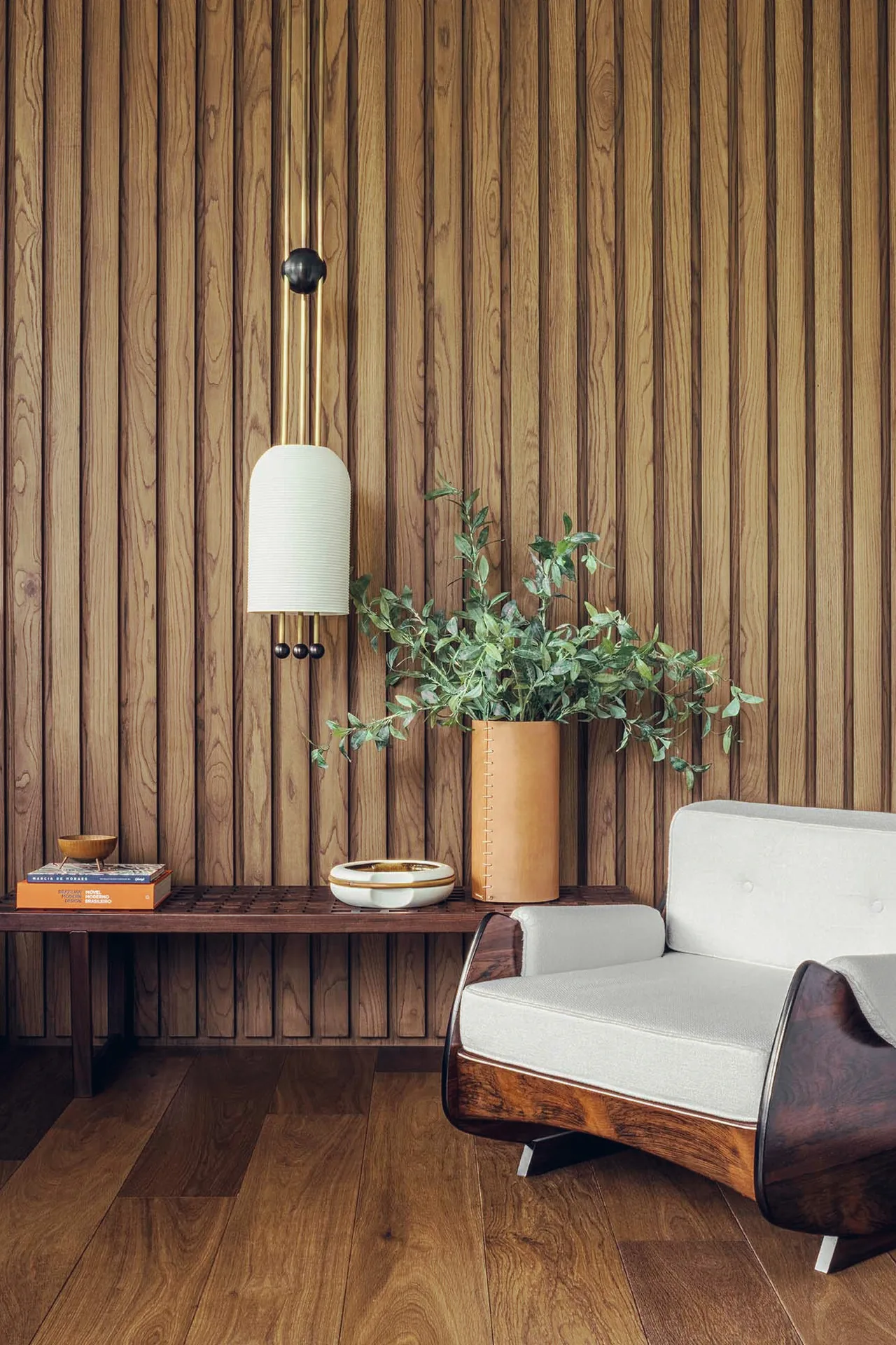 Living area with vertical wood panel wall, a cushioned armchair, and a decorative bench.