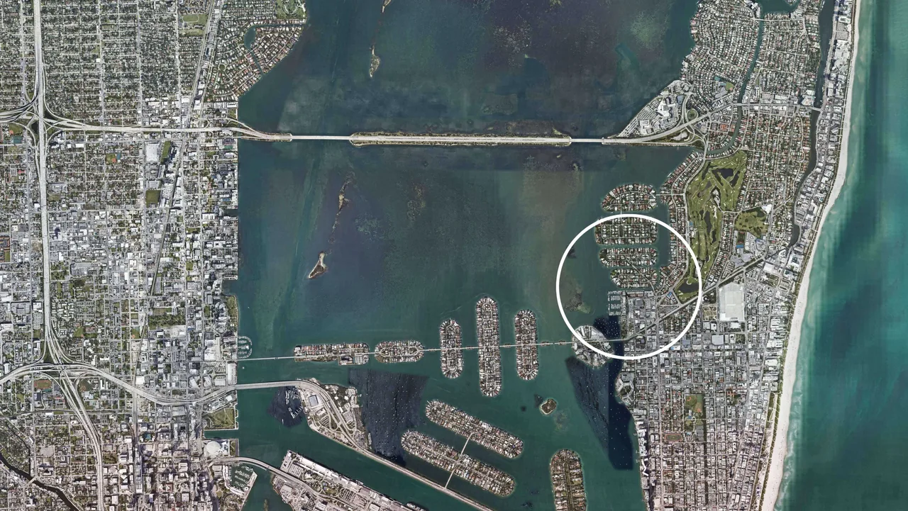 Aerial photo showing residential islands, waterways, a bridge, and urban grid near the coast in Miami.