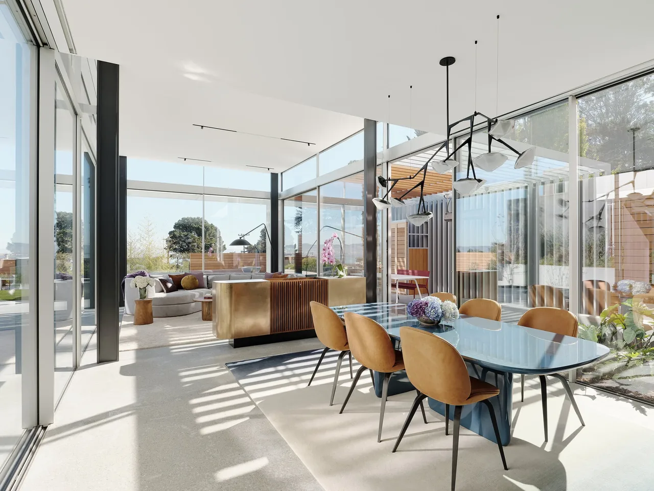 Open dining and living area with floor-to-ceiling glazing and a sliding glass door overlooking a courtyard space.