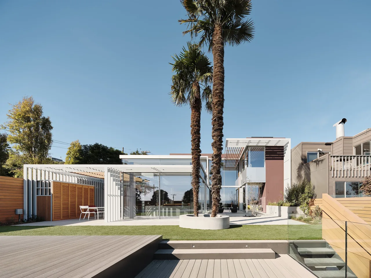 The Translucence project features a modern home with floor-to-ceiling glazing and a vertical slat pergola in the exterior rear courtyard.