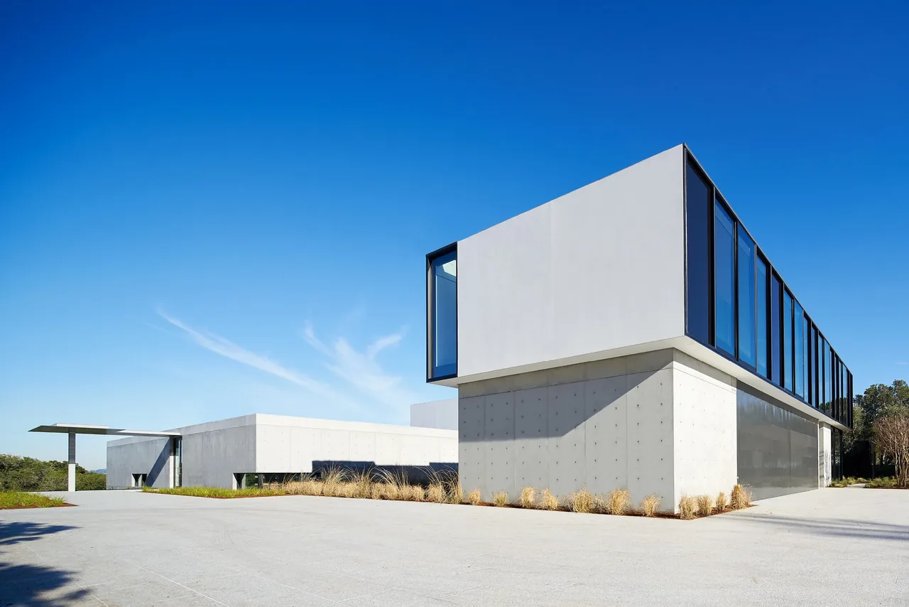 The OZ Residence features a cantilevered volume with concrete walls and large black-framed windows.