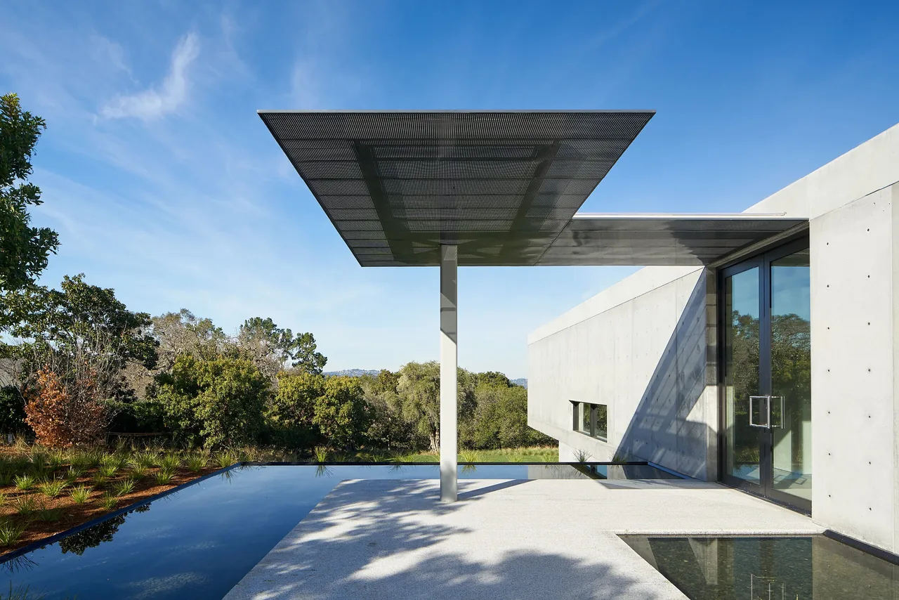 OZ Residence shows a cantilevered metal canopy, patterned concrete walls, and reflecting pool edges with landscaped surroundings.