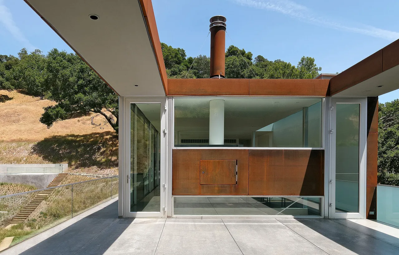 Modern exterior front of Bridge House with steel framing, large glass walls, and flat roof.