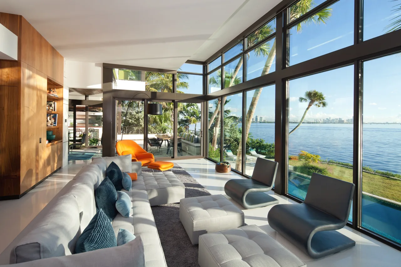 Living room with large corner windows and clerestory glazing offering expansive water views at Coral Gables Residence.