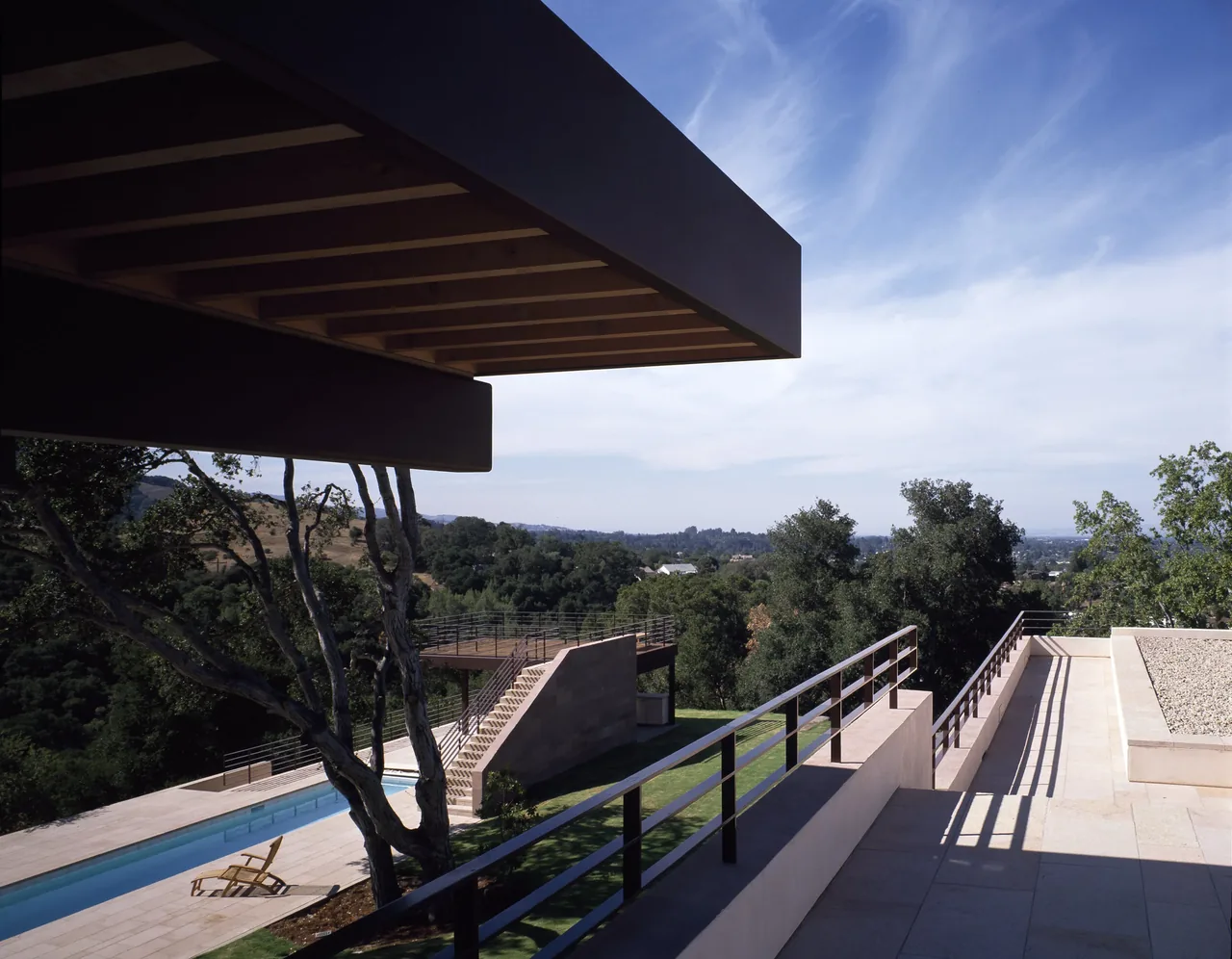 Di Napoli Residence terrace with metal railing, tiered stone steps, and pool amid hillside landscape.