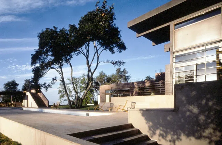 The Di Napoli Residence features a stone courtyard and metal railings, positioned on a hilltop with urban views.