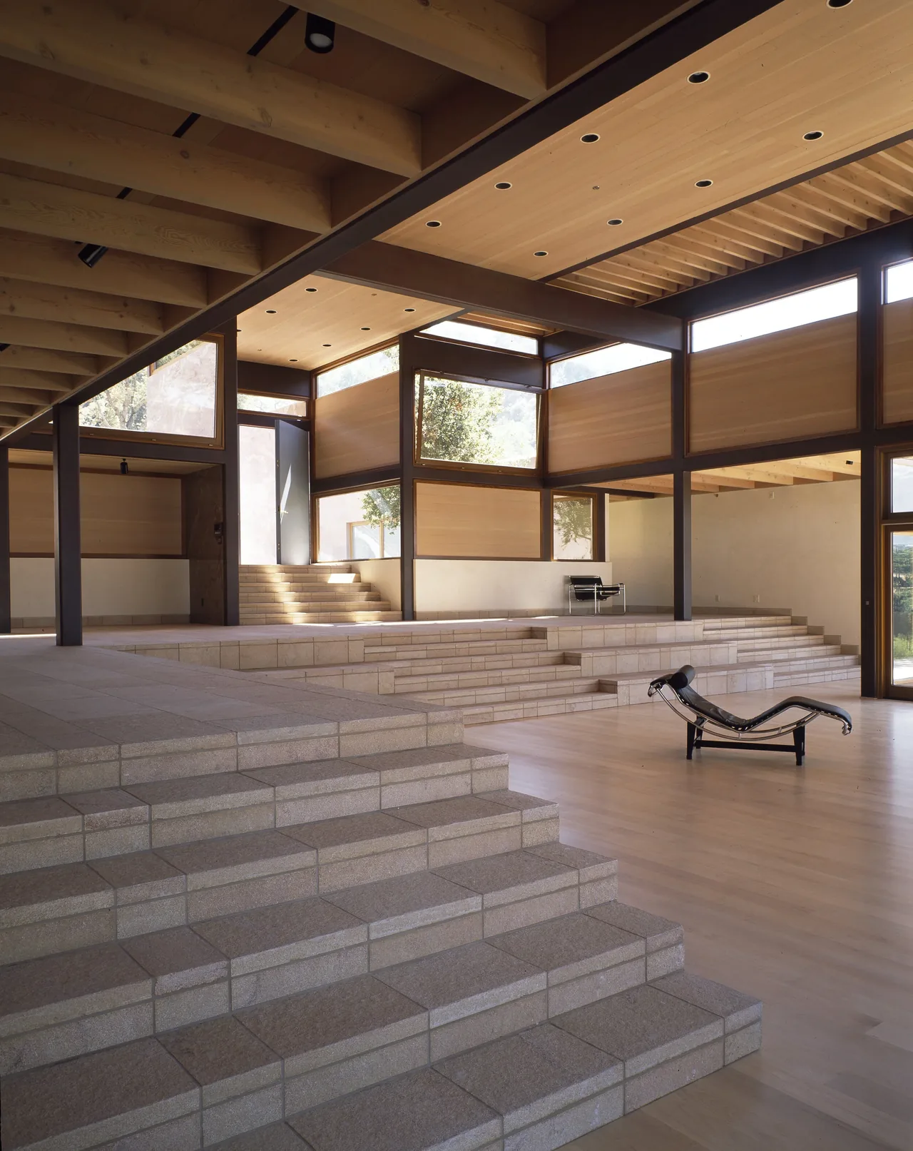 Di Napoli Residence features tiered stone steps and wood ceiling beams with abundant window daylighting.