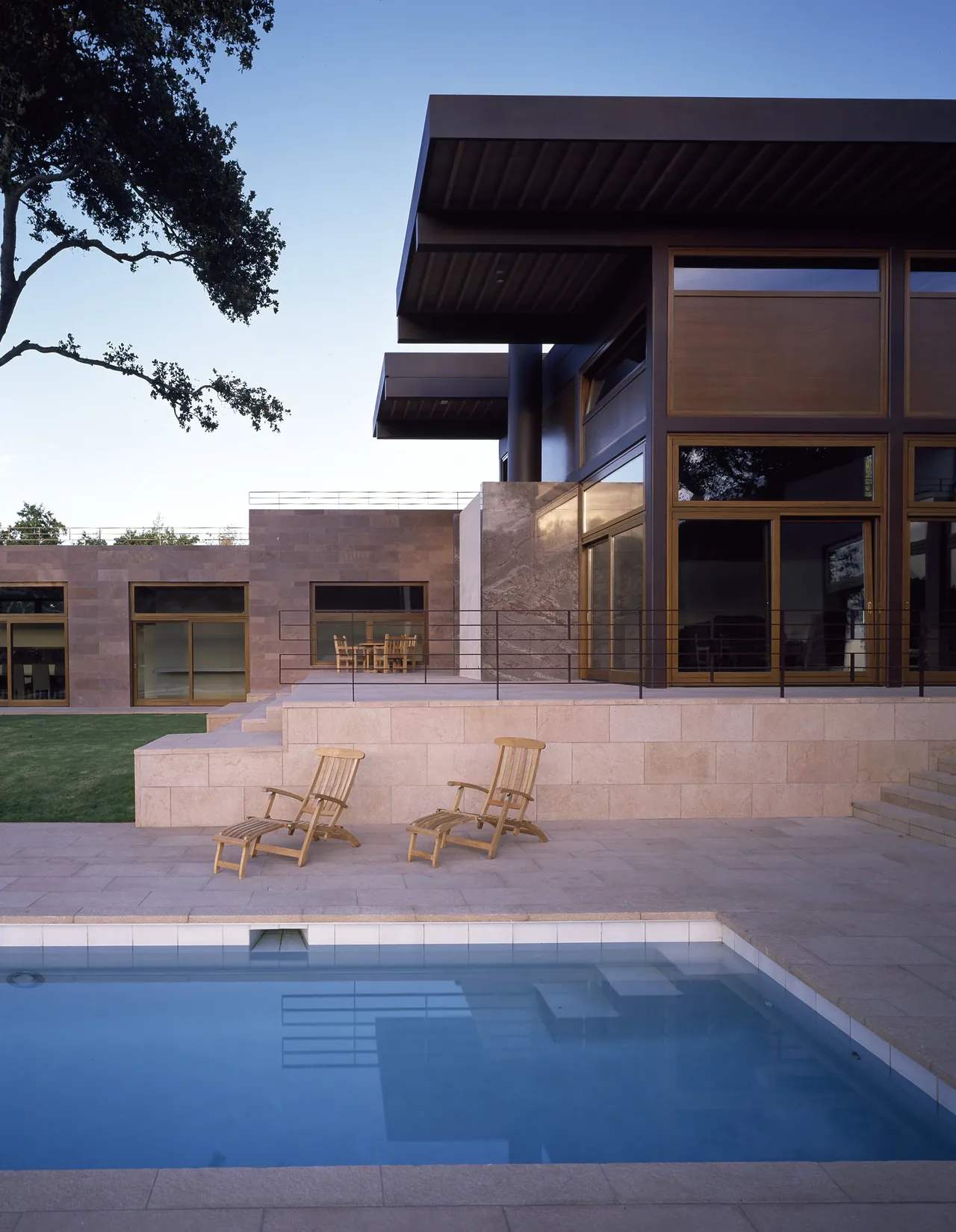 The Di Napoli Residence features flat roof overhangs and a pool terrace with wooden lounge chairs.