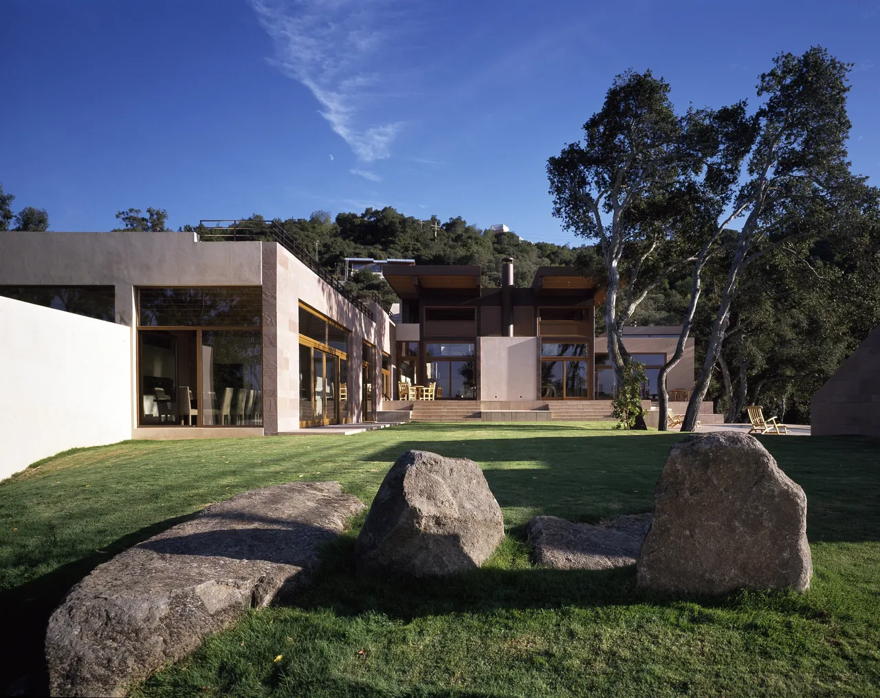 Di Napoli Residence features flat roofs, stone and stucco walls, and large wood framed windows overlooking a landscaped courtyard.