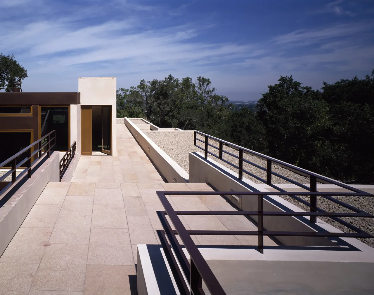 Terrace with stone tile floor and metal railings at the Di Napoli Residence by Stanly Saitowitz | Natoma Architects.