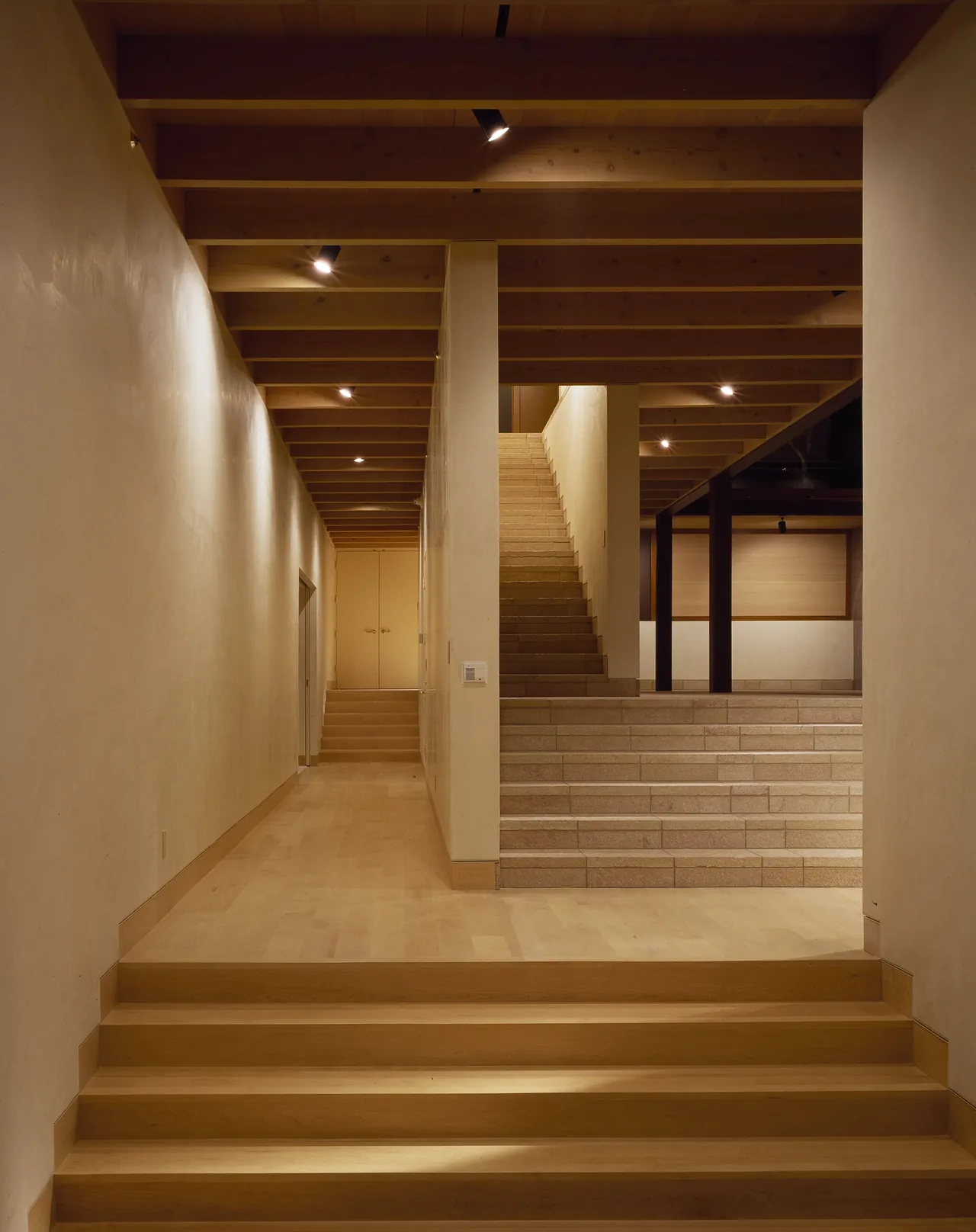 Di Napoli Residence features a tiered staircase with wooden ceiling beams and stone steps, designed by Stanly Saitowitz | Natoma Architects.