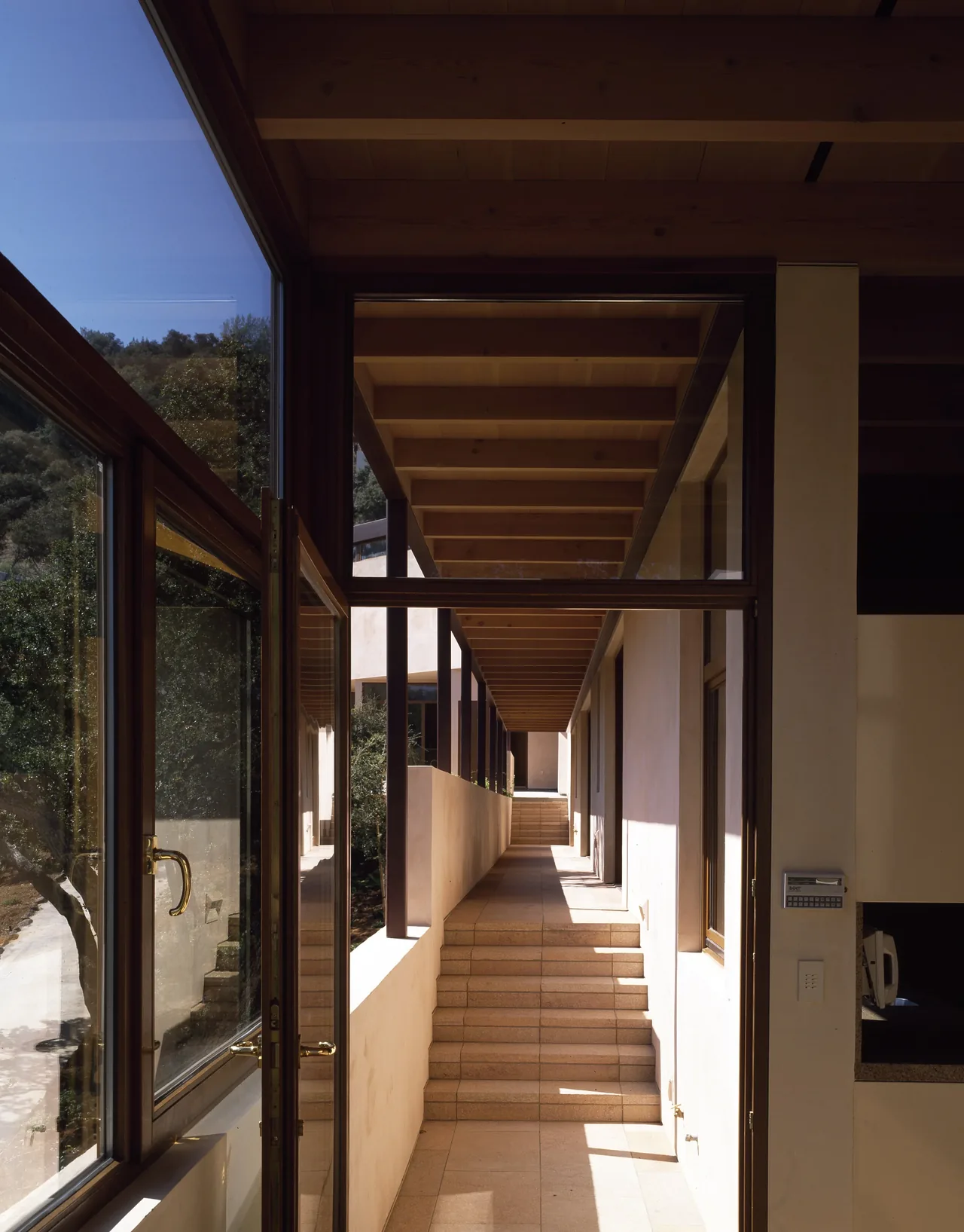 Outdoor corridor with tiered stone steps and exposed wood beam ceiling at Di Napoli Residence.