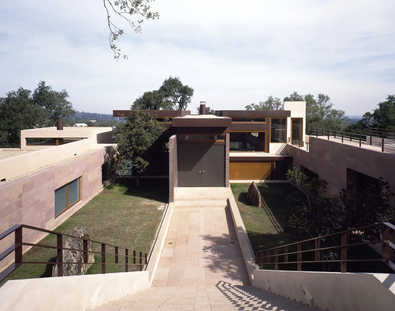 Di Napoli Residence shows a modern design with stone walls, courtyards, and a central ramp entry.