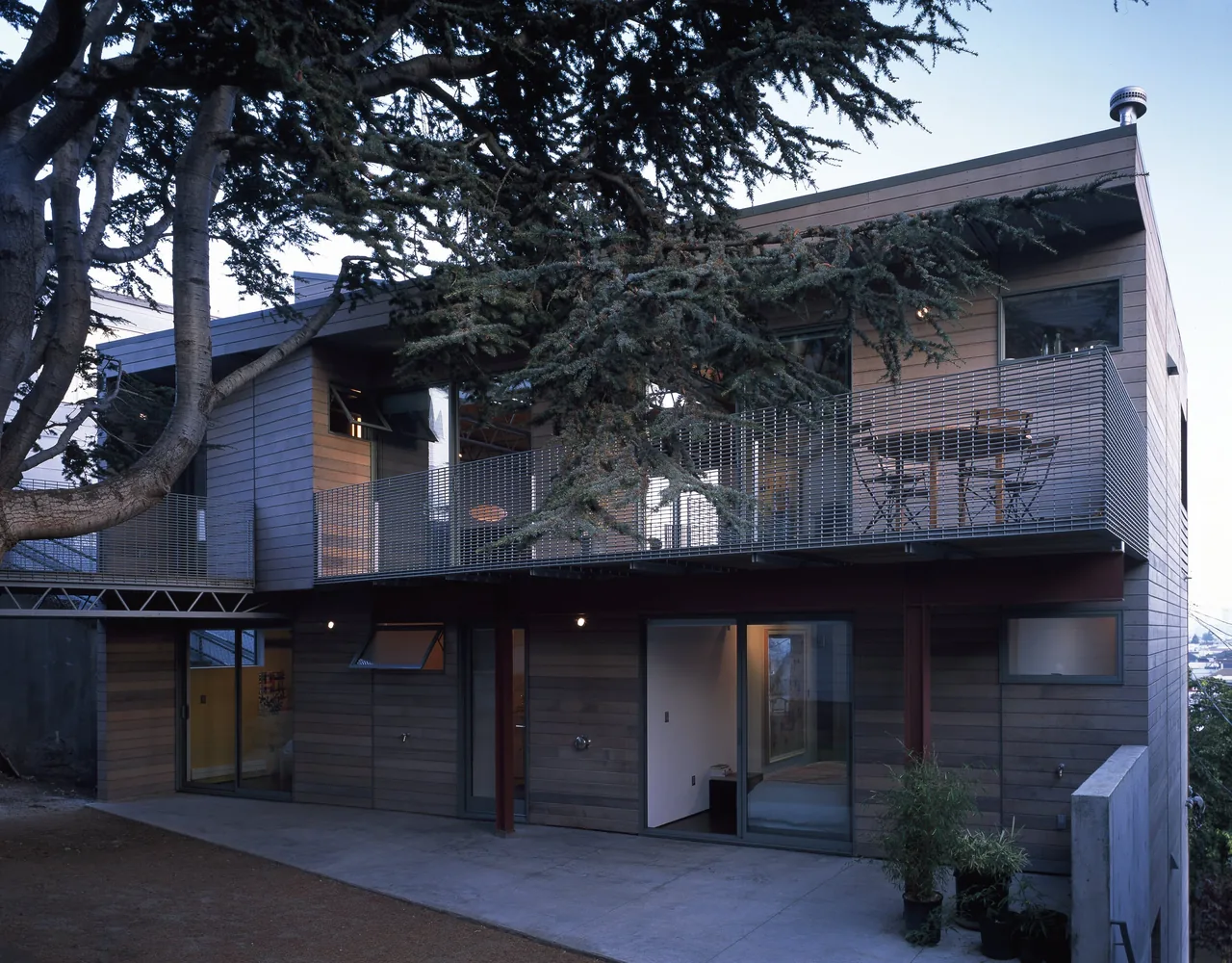 The Barnes Residence features wood-paneled siding and a narrow balcony with metal mesh railing on a sloped site.