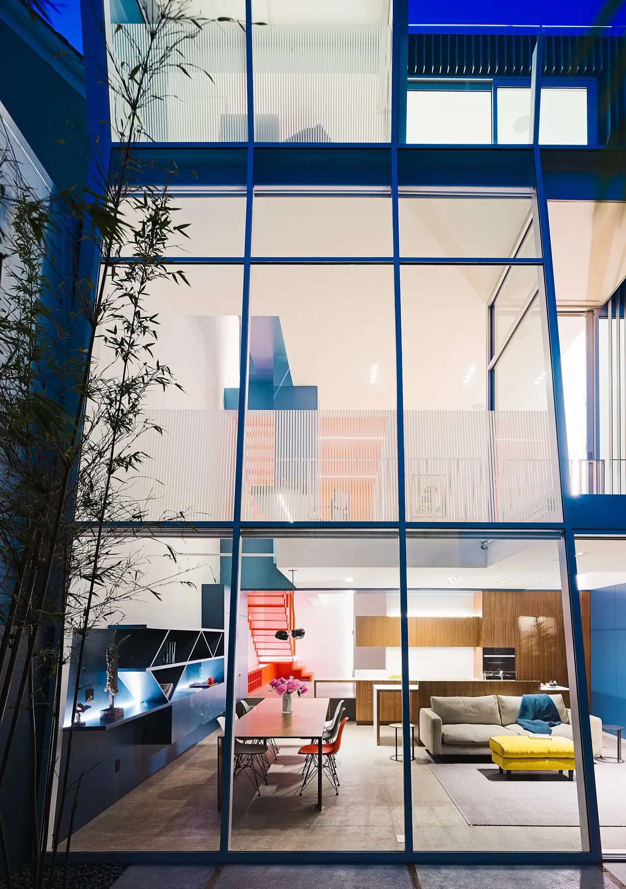 Modern open-plan kitchen and living area seen through tall windows in the Cut Out House project.