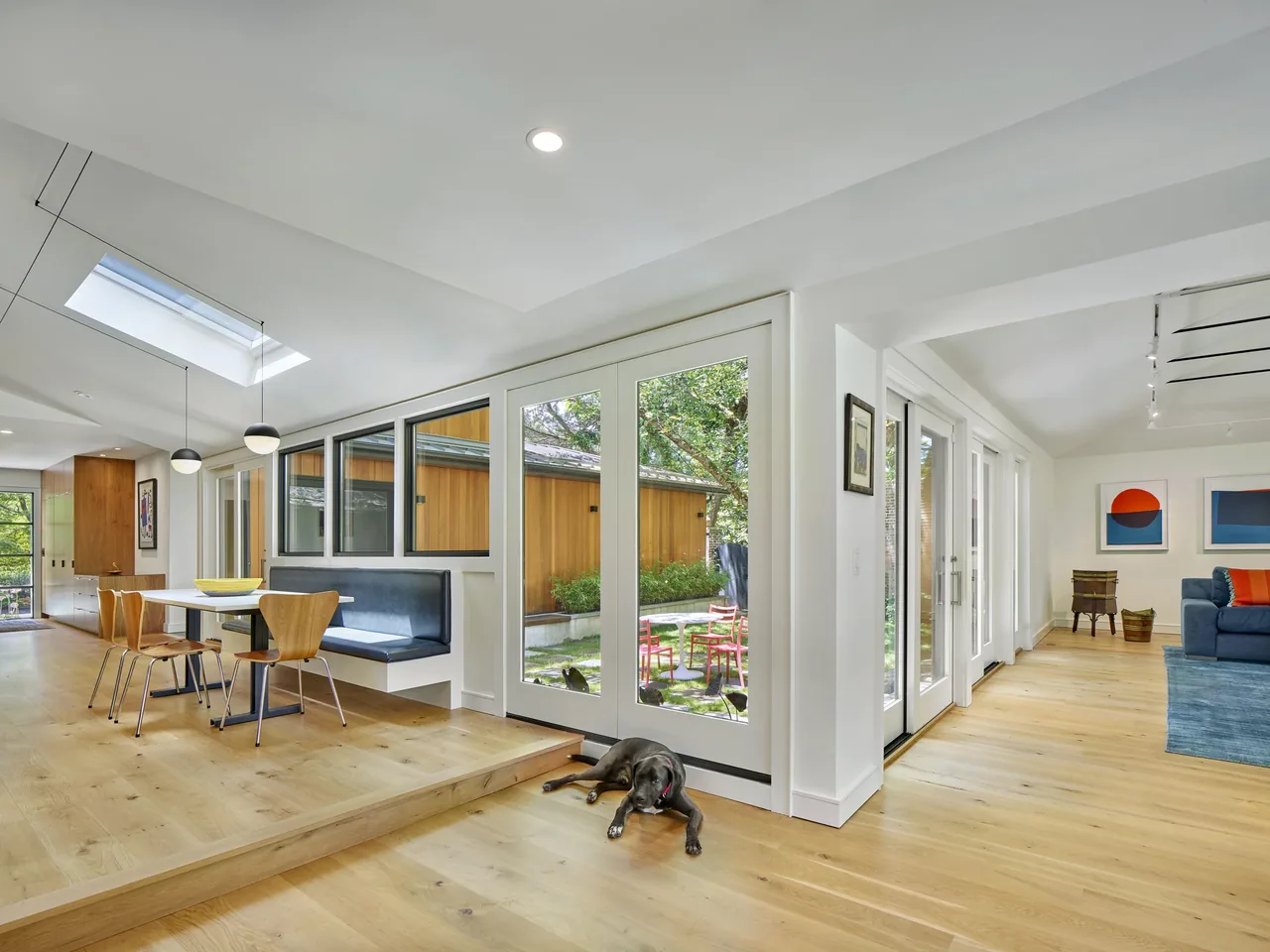 Open dining and living space with floor-to-ceiling glazing and skylights overlooking an outdoor courtyard
