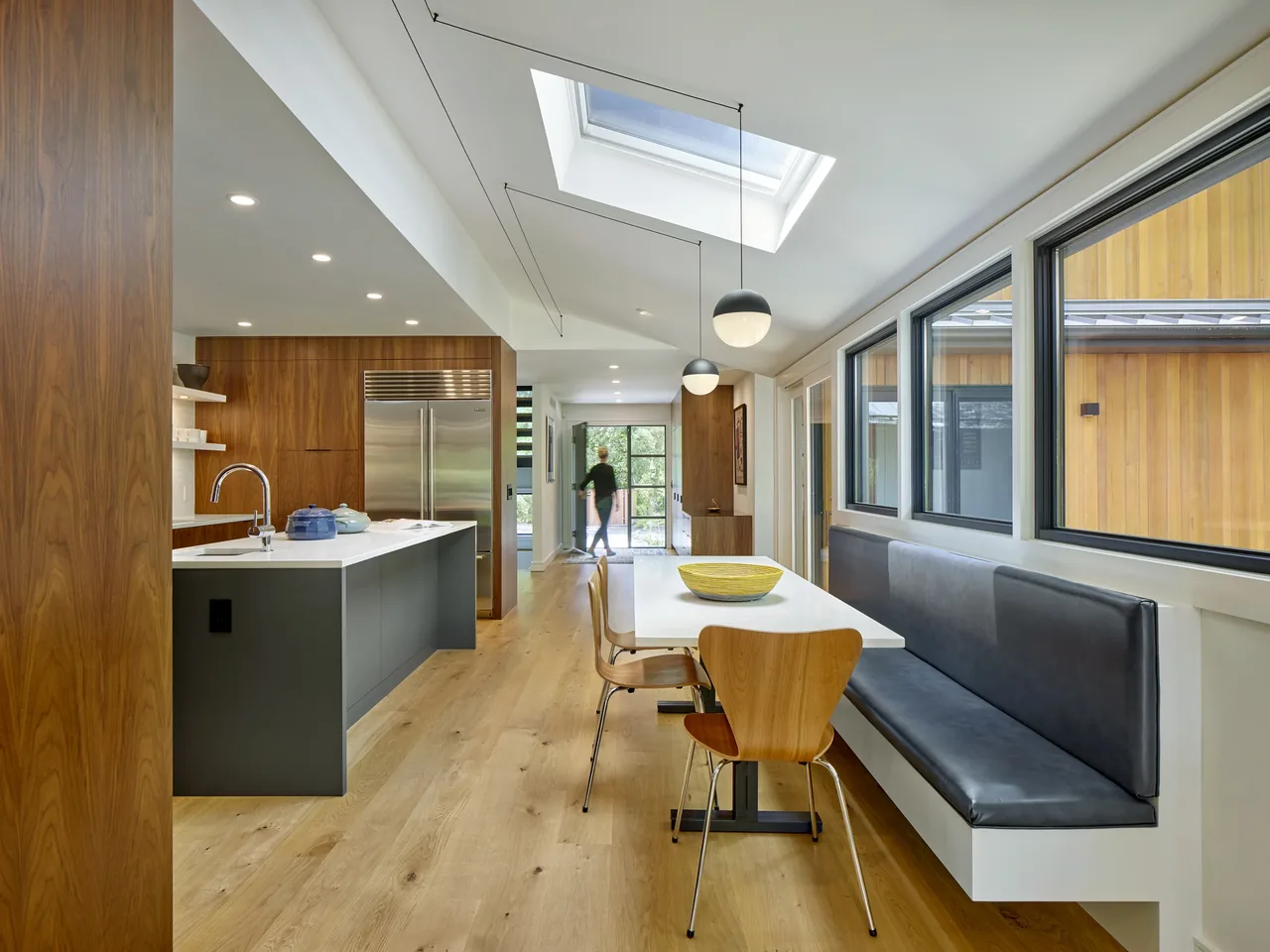 Contemporary kitchen and dining area featuring wood flooring, built-in banquette, and skylight.