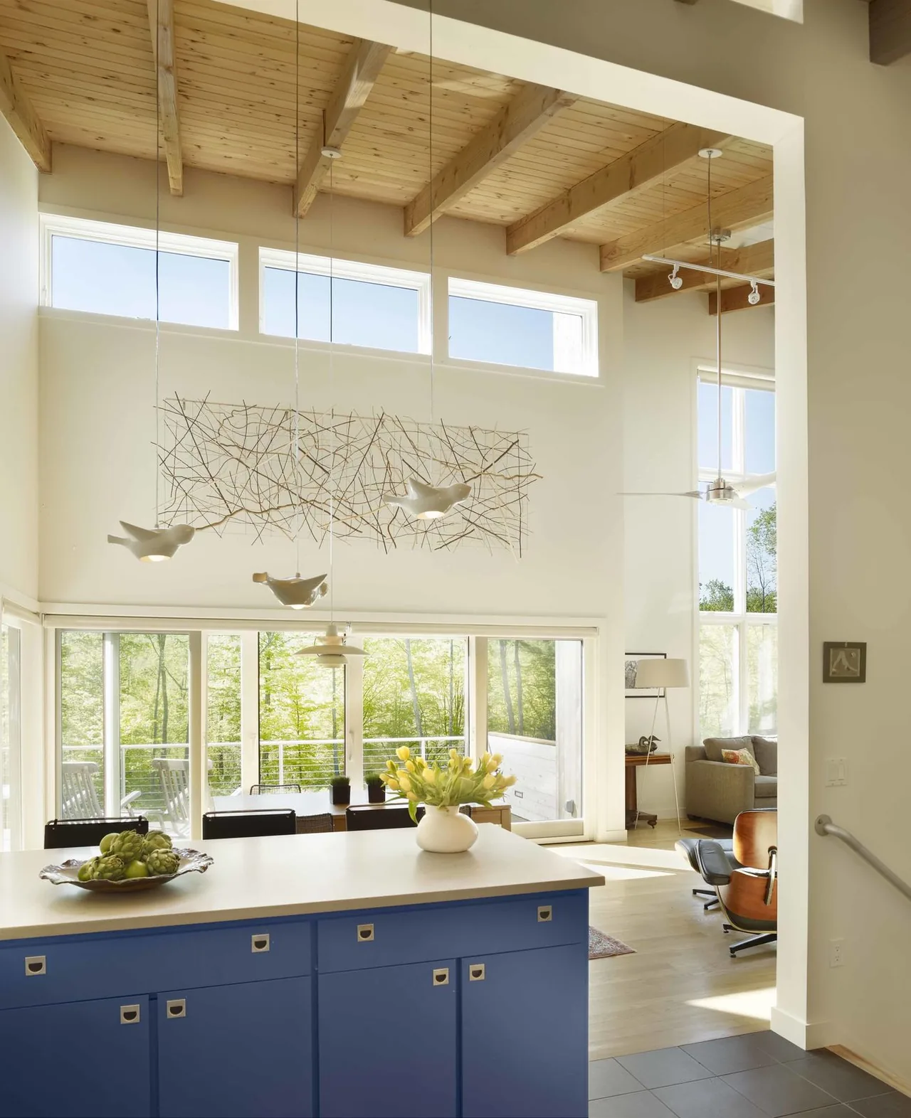 Modern kitchen and living space with exposed wood beam ceiling, clerestory windows, and large sliding glass doors.