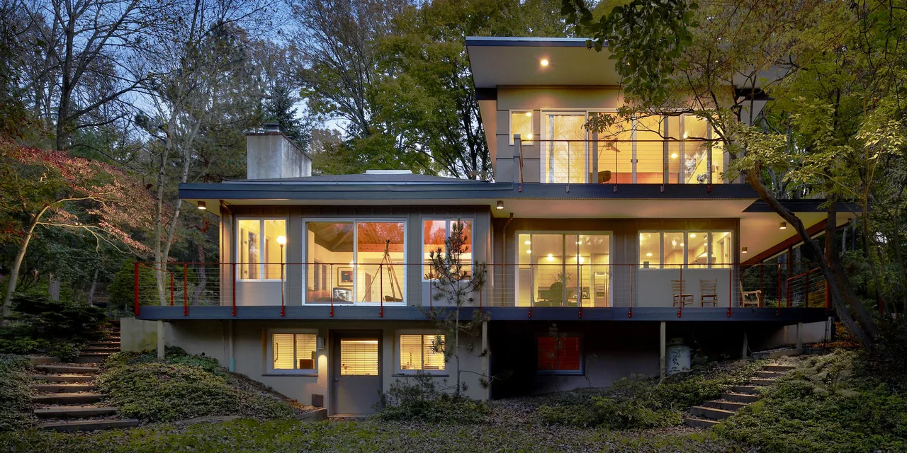 Evening view of Seidenberg House showing illuminated interiors and outdoor landscape.
