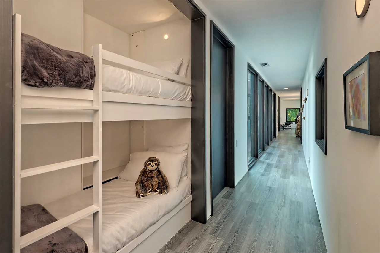 Hallway with black window frames and a built-in white bunk bed in a residential interior.