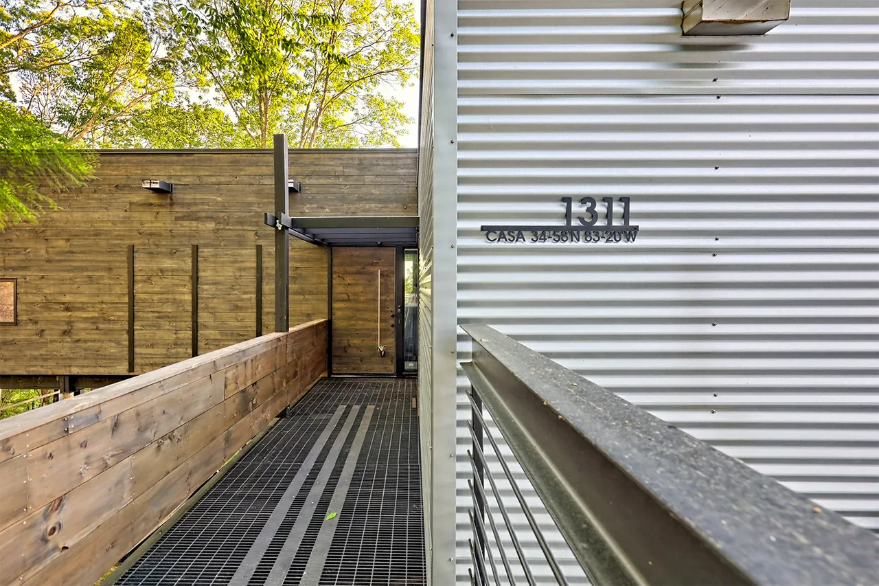 Entrance corridor with metal grating floor and wooden wall alongside corrugated metal siding marked 1311 CASA 34°58'N 83°20'W.