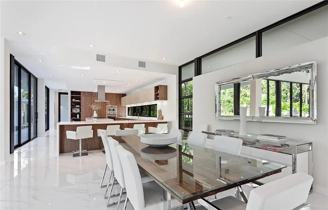 Open dining area and kitchen with large floor-to-ceiling glass windows and recessed lighting.