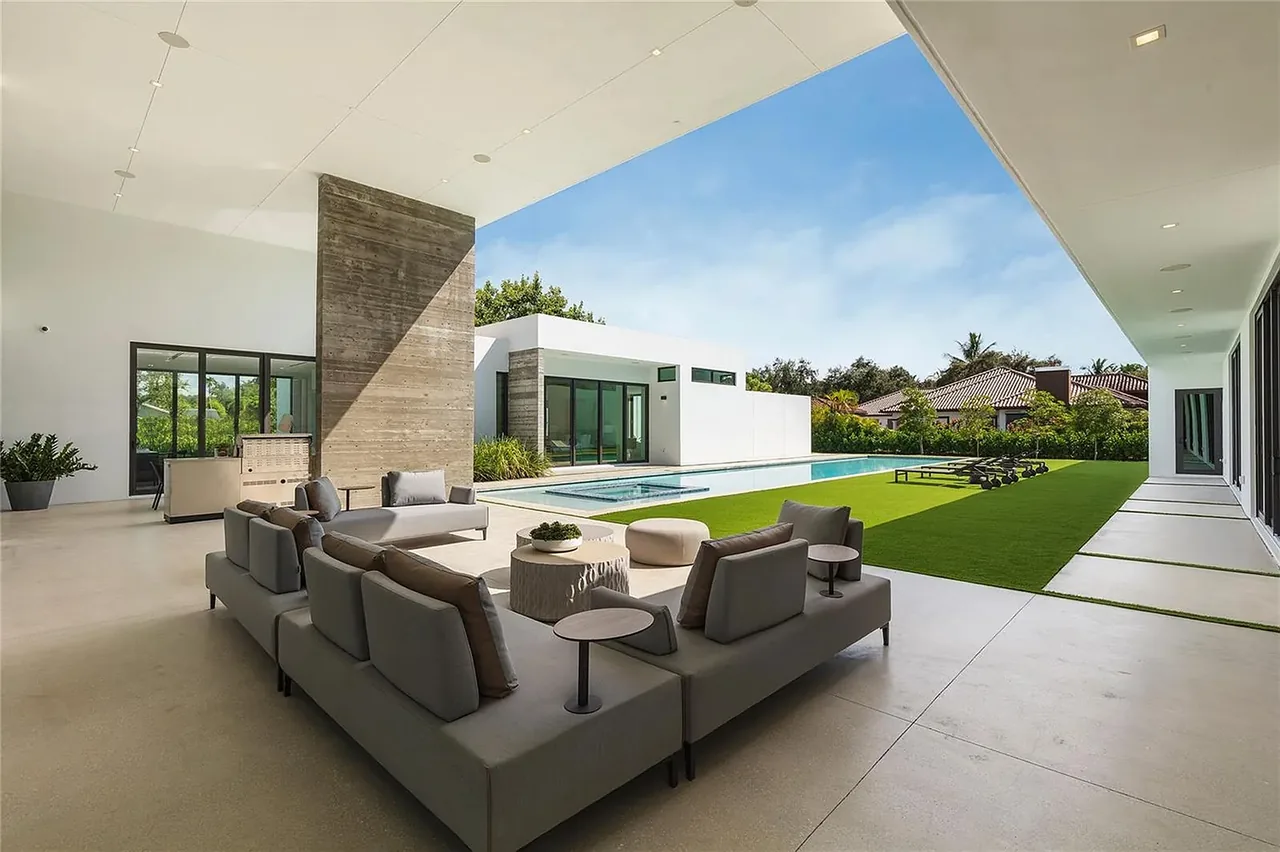 Covered patio area at CASA BARSKY with modern outdoor furniture, pool, and landscaped lawn in Miami.