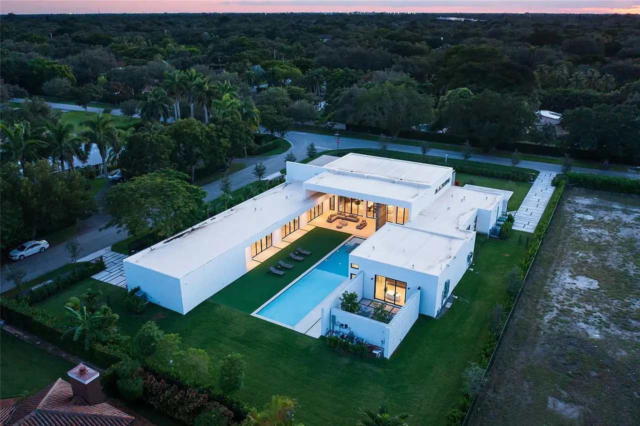 Casa Barsky features a U-shaped modern design with a flat roof, long swimming pool, artificial grass, and outdoor seating.