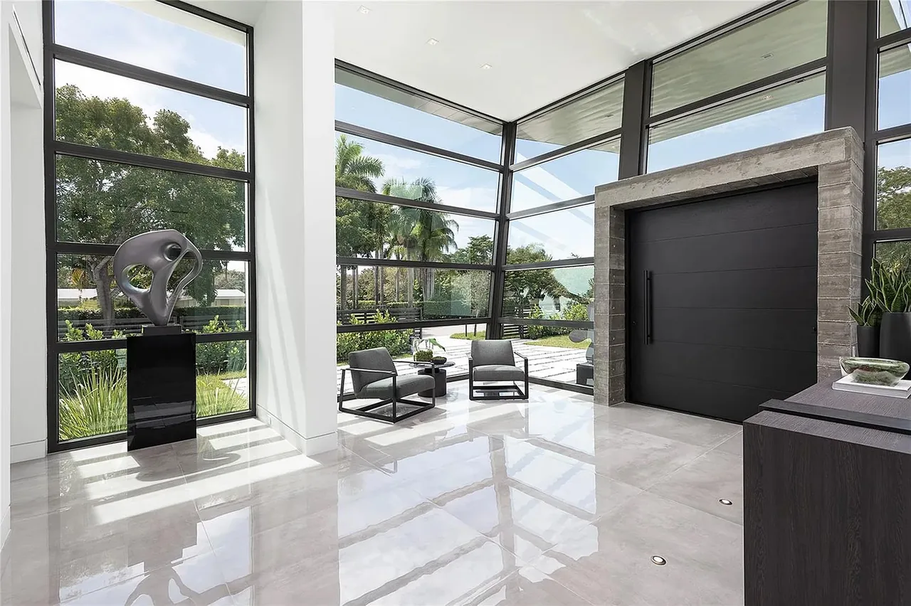 Entry space featuring floor-to-ceiling corner glazing and a black pivot door in CASA BARSKY.