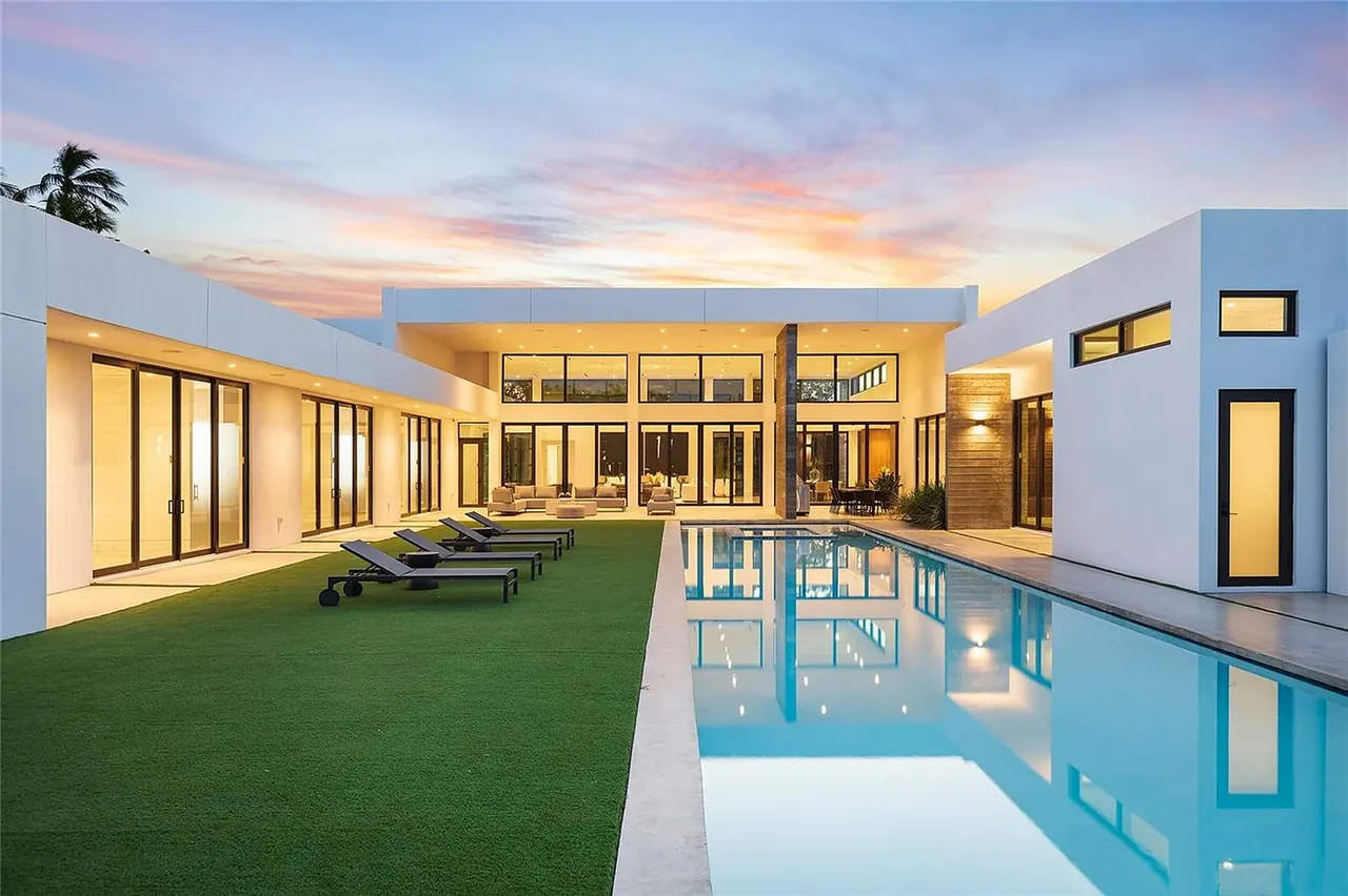 CASA BARSKY features a modern exterior with a swimming pool and manicured lawn at sunset by Mateu Architecture.