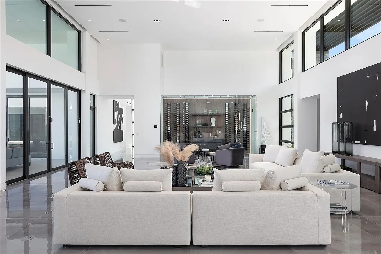 Living area featuring large black-framed windows, white upholstery, and polished floor tiles in CASA BARSKY.