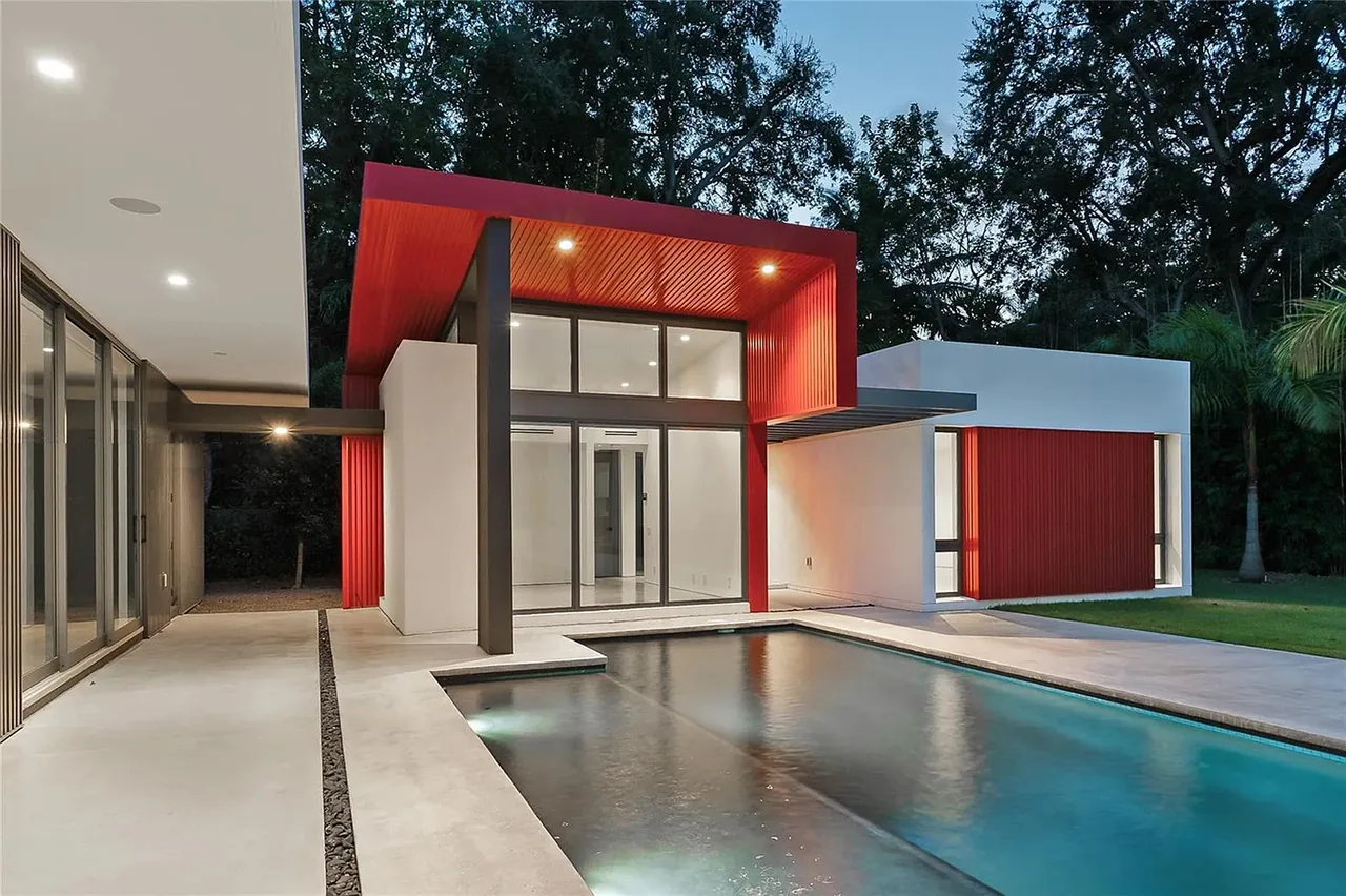 CASA BOUGAINVILLEA features modern architecture with floor-to-ceiling windows and a pool adjacent to a covered patio.