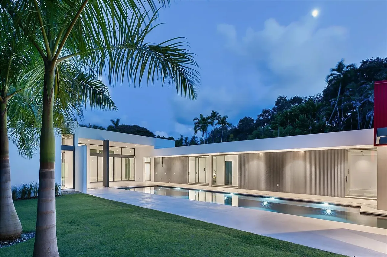 CASA BOUGAINVILLEA features a modern exterior with a long pool and large sliding glass doors opening to a patio area.