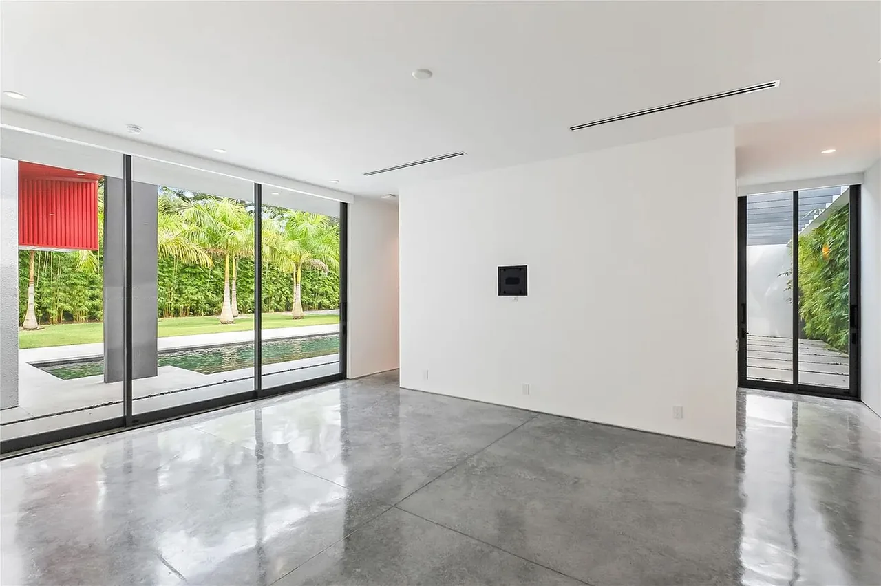 Living room in CASA BOUGAINVILLEA with polished concrete floor and floor-to-ceiling windows showcasing a pool and greenery.