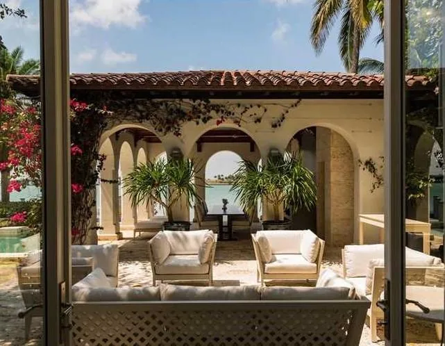 Outdoor seating area at Sunset Island Residence with stone columns and arched openings facing the water.