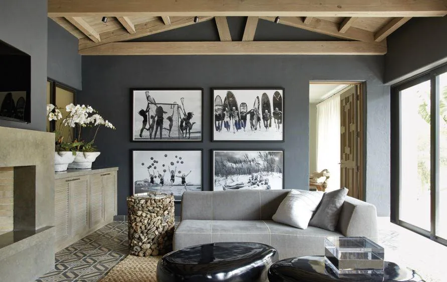 Living room with exposed wood beams, black and white photos, and a gray sofa in Venetian Island Residence.