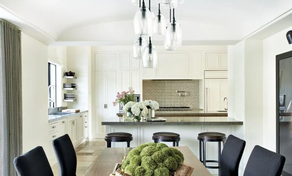 Venetian Island Residence kitchen features white cabinetry, geometric tile backsplash, and pendant lighting over the island.