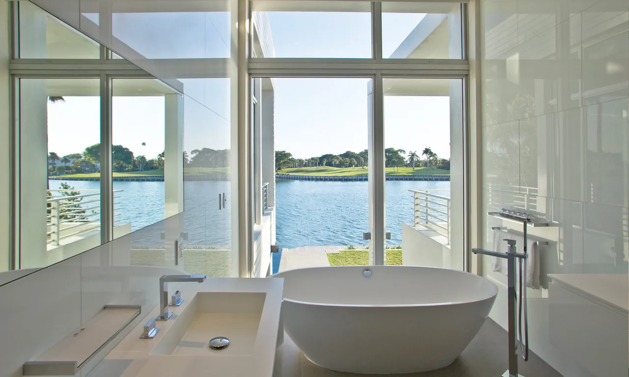 Bathroom featuring a freestanding tub and floor-to-ceiling glazing with a waterfront view.