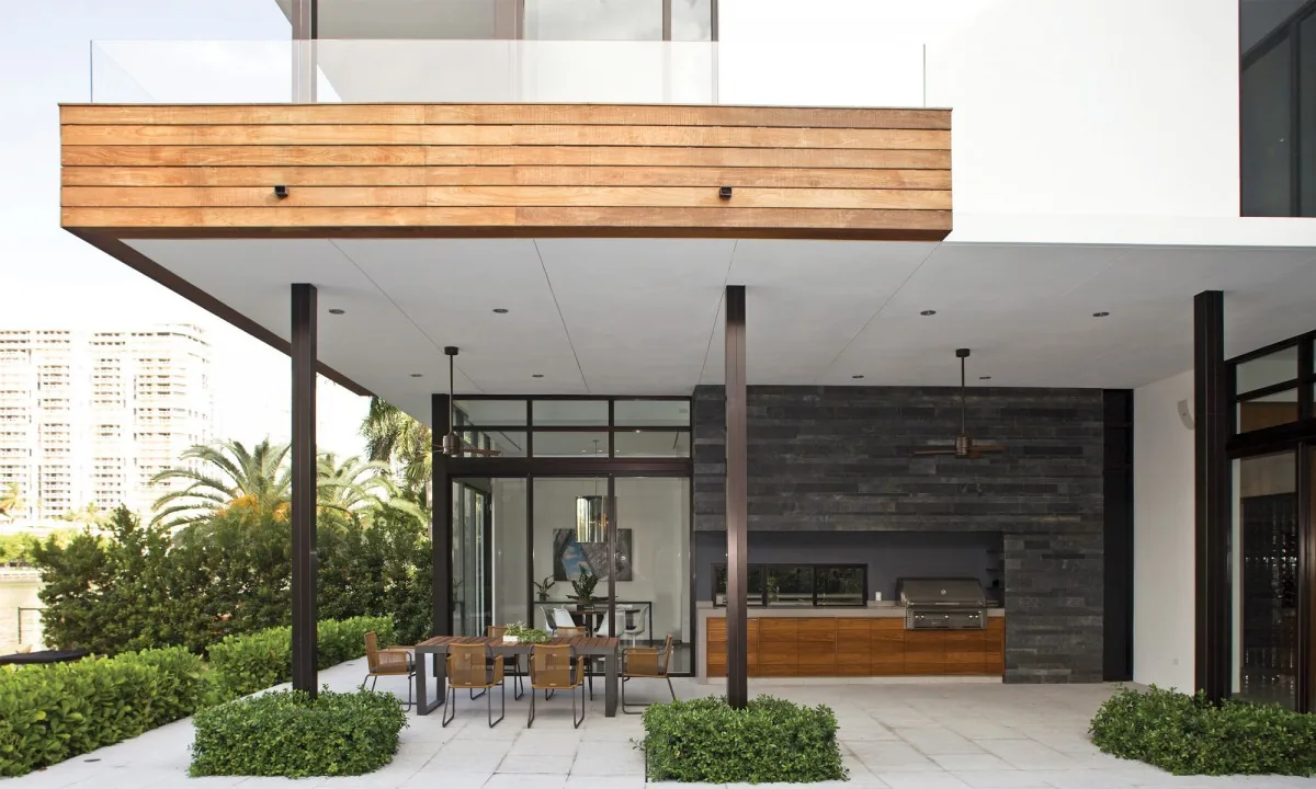Covered outdoor patio area featuring stone wall, wood ceiling paneling, and dining furniture.