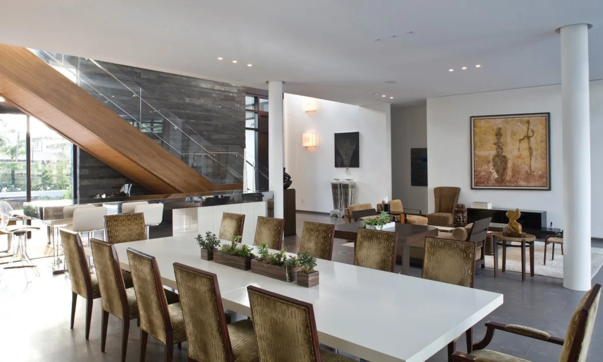 Interior view of a dining and living area with a wooden staircase and modern furnishings.