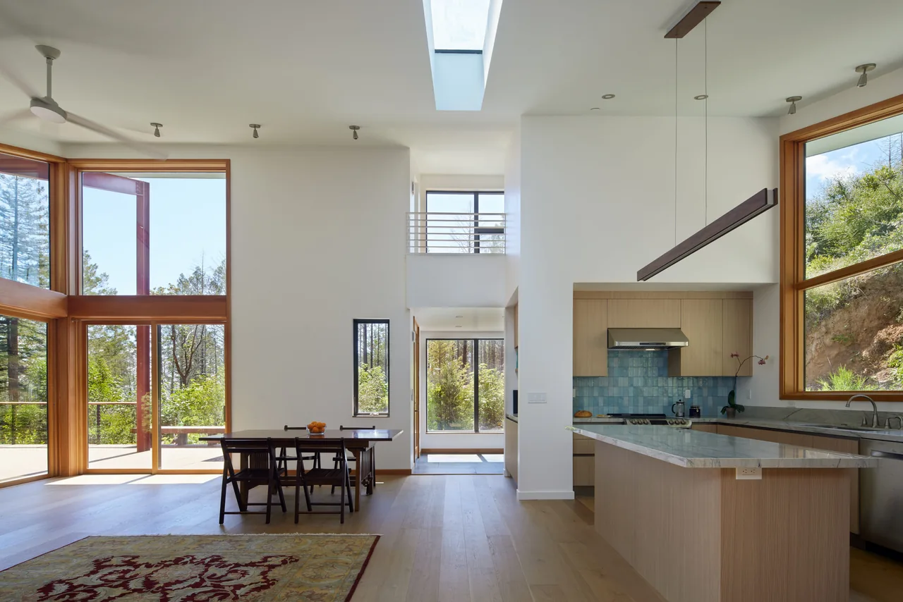 Modern kitchen and dining area with floor-to-ceiling glazing and a skylight providing natural light.