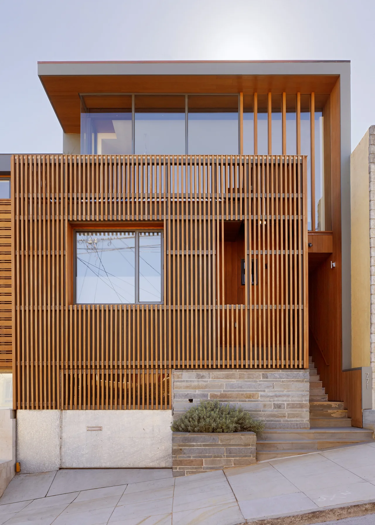 The Vessel features a vertical wood slat facade combined with large glass windows and a stone foundation wall.
