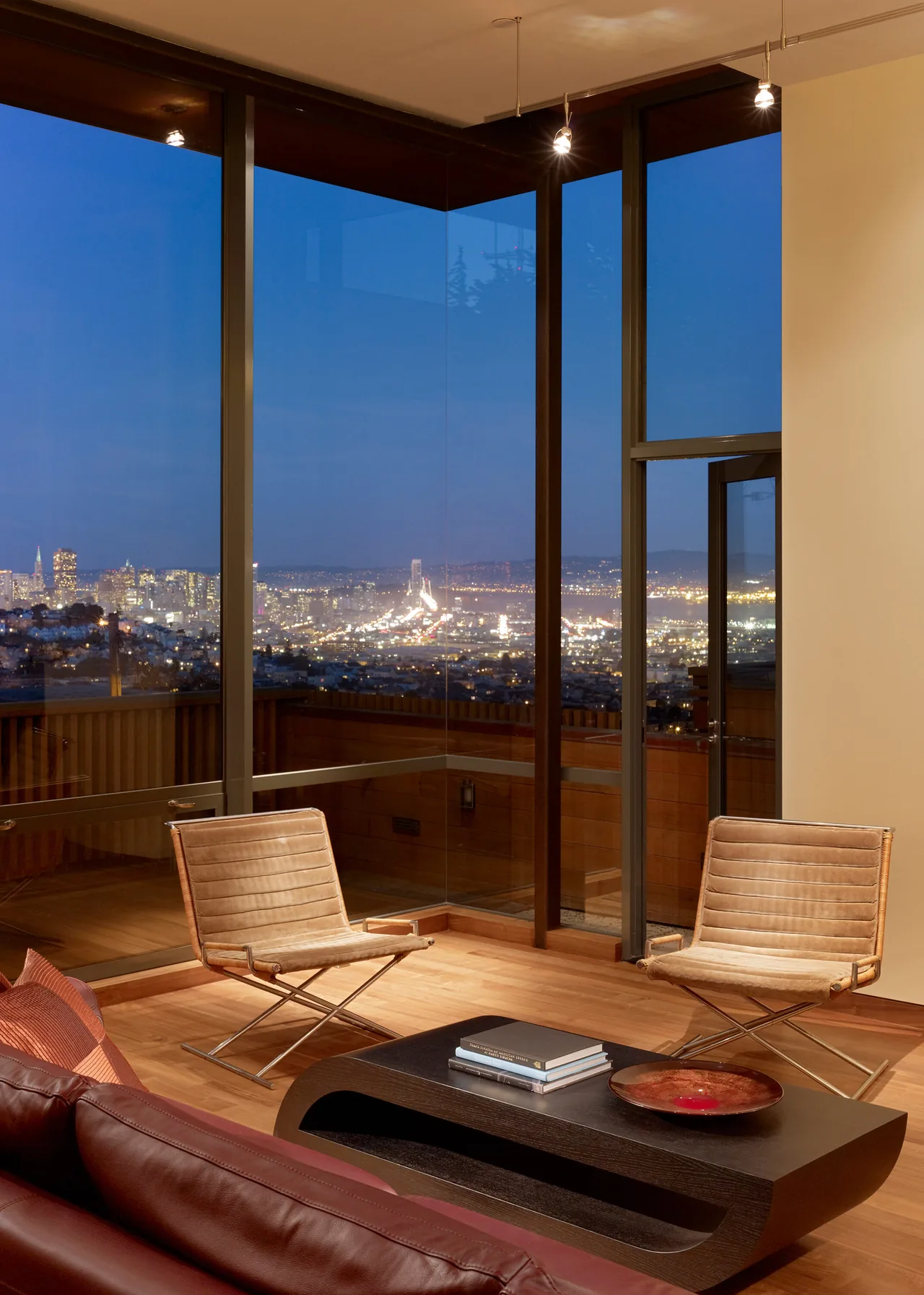 The Vessel features corner windows in a living space overlooking the San Francisco cityscape at dusk.