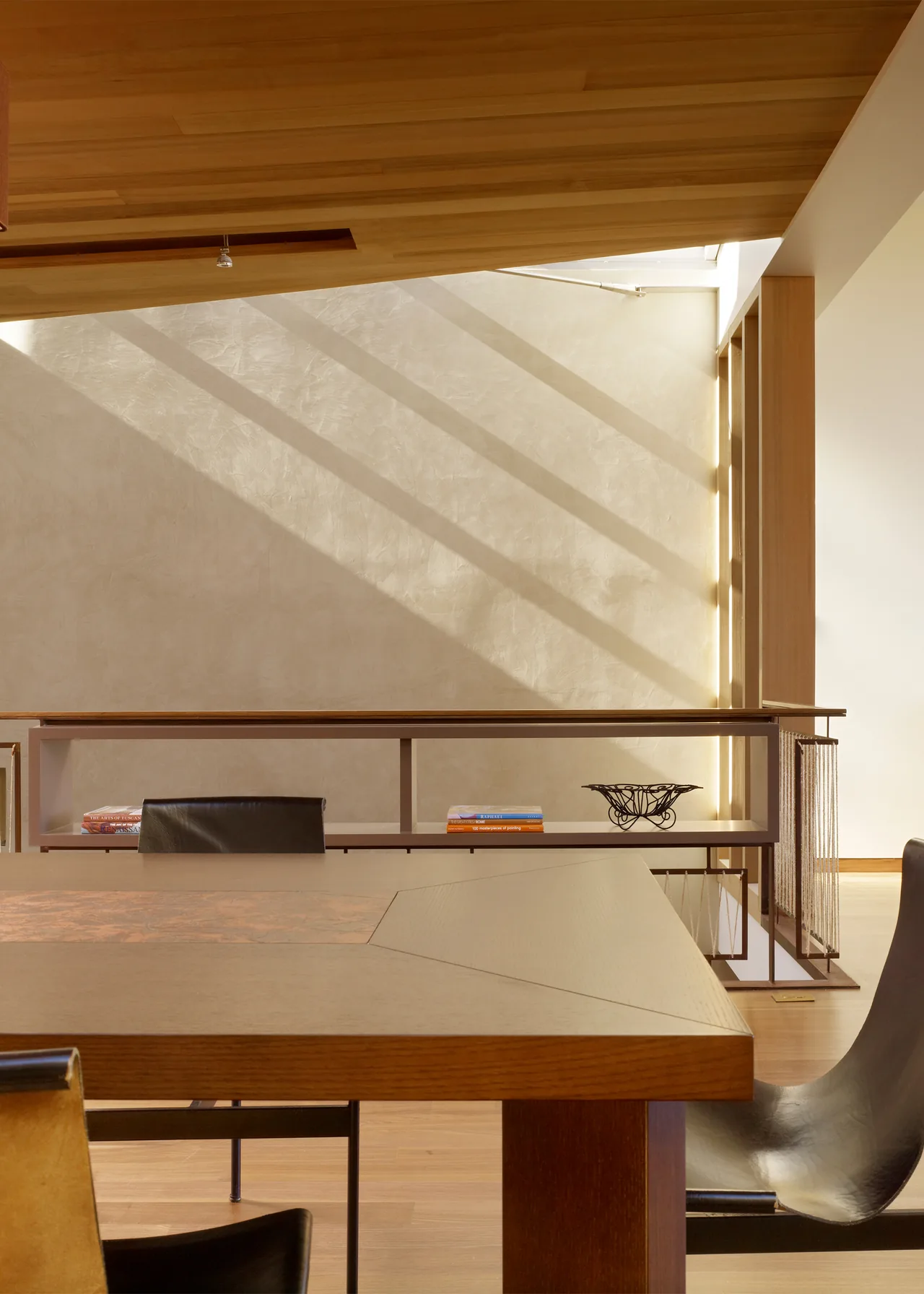 Modern dining space with wood ceiling, textured plaster wall, and minimalist furniture in The Vessel project.