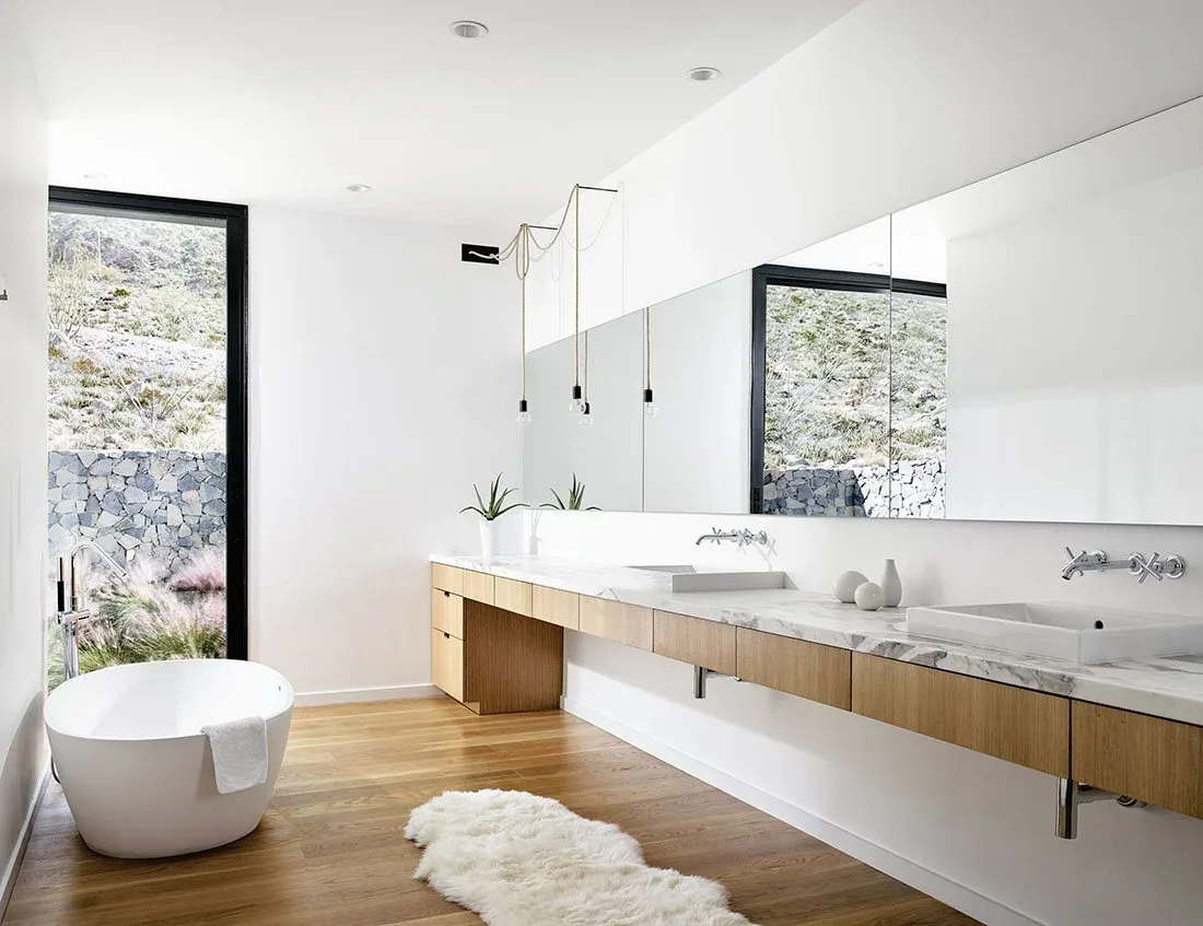 Bathroom features a floating wood vanity with marble top, two sinks, and a freestanding tub near floor-to-ceiling glazing.
