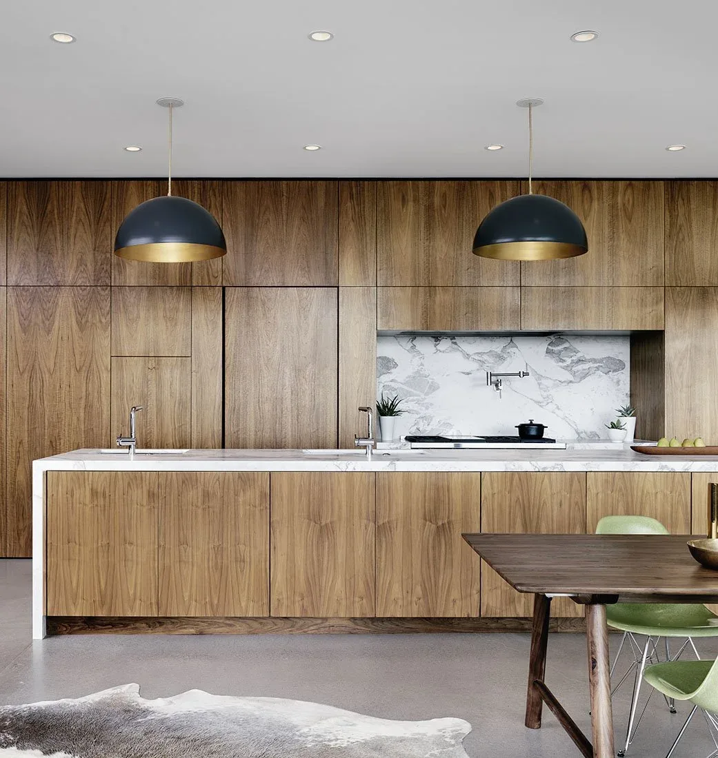 Kitchen featuring wood cabinets, white marble countertop and backsplash, and black and gold pendant lights.
