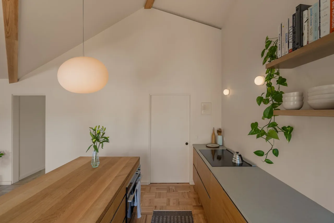 Kitchen featuring a wooden island, vaulted ceiling with exposed beams, and floating shelves.