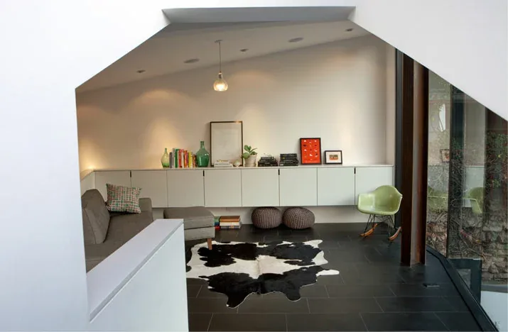 Interior view of a modern living room featuring a corner window and minimalist furnishings.
