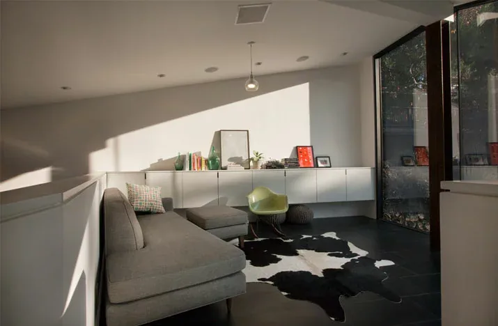 Living room featuring a gray sectional sofa, floating cabinets, and a corner window with natural light.